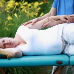 physical therapist massaging pregnant woman's arm