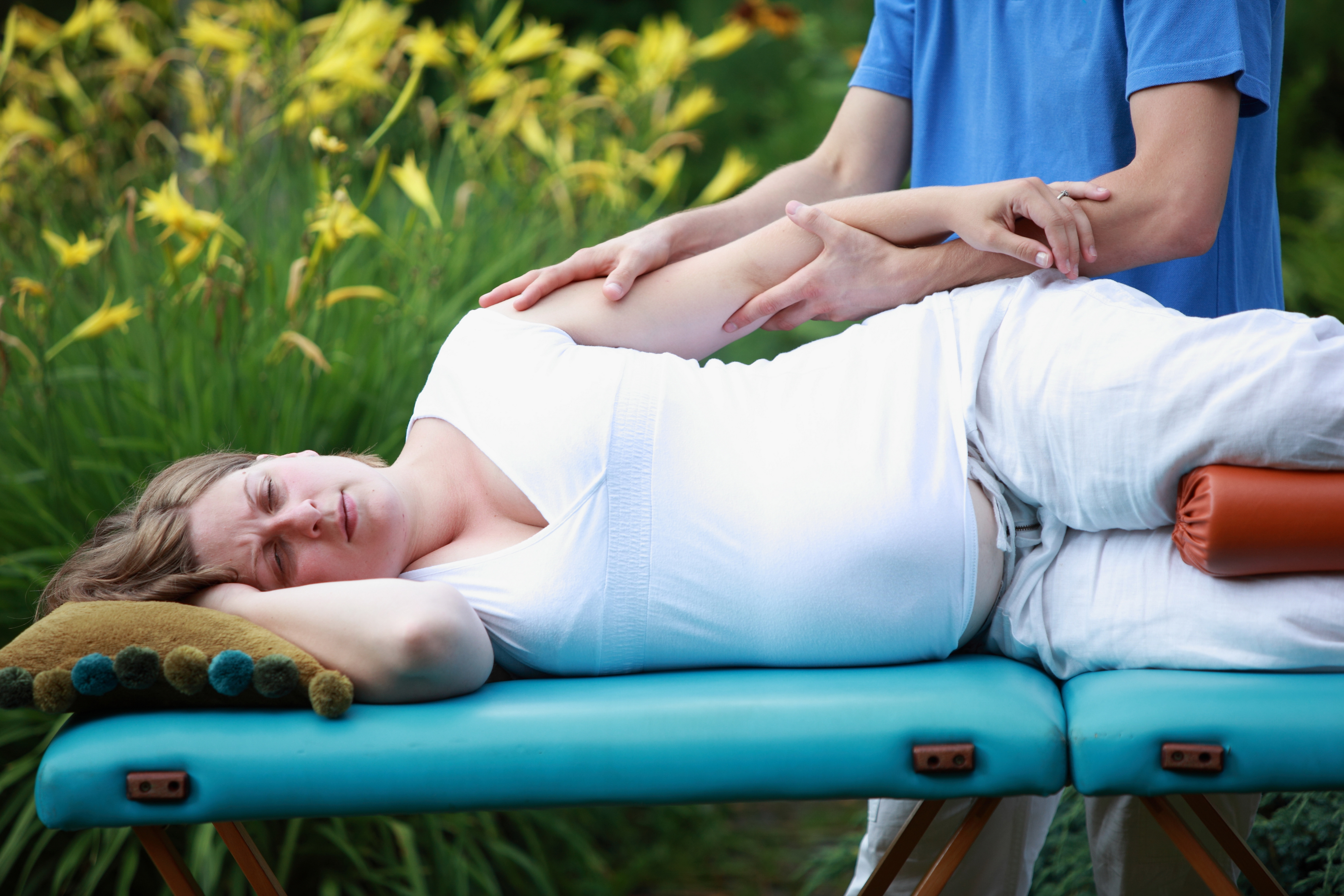 physical therapist massaging pregnant woman's arm